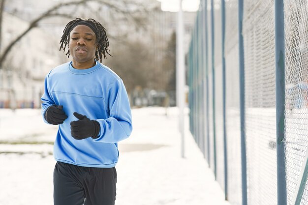 겨울 공원에서 남자. 아프리카 남자 훈련 밖에. 남자가 달린다.