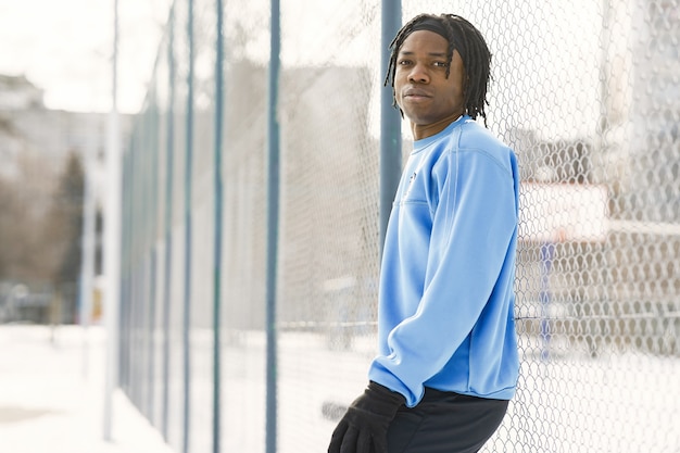 Man in a winter park. African guy training outside.