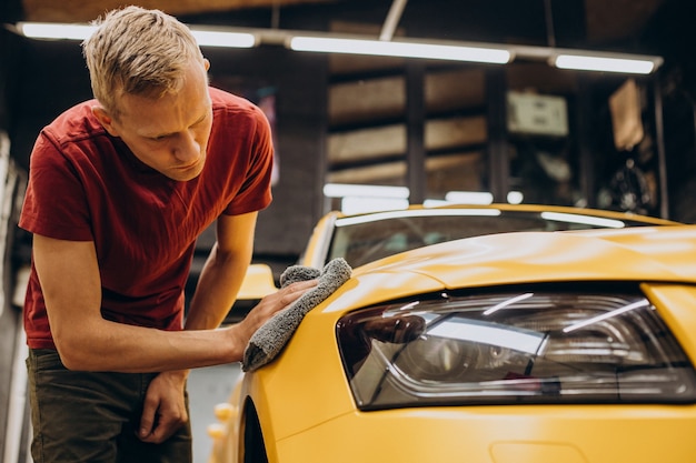 Free photo man wiping car with microfiber after wash