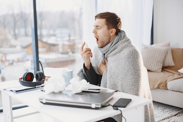 ノート​パソコン​を​持っている​男性​は​咳​に​苦しんでいて​気分​が​悪い​です​。​自宅​で​ビジネスマン​。