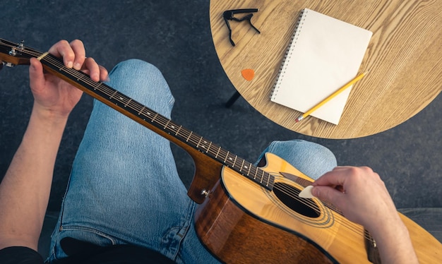 Un uomo con una chitarra acustica e un quaderno sul tavolo