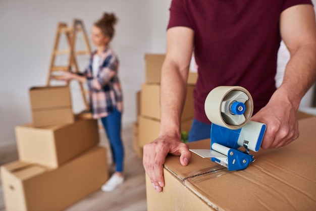 Man with adhesive tape packing boxes