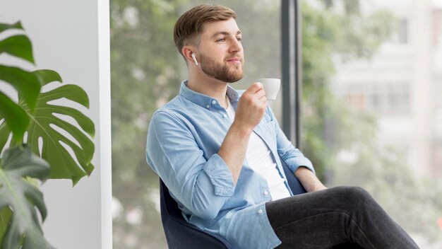 コーヒーを飲むairpodsを持つ男