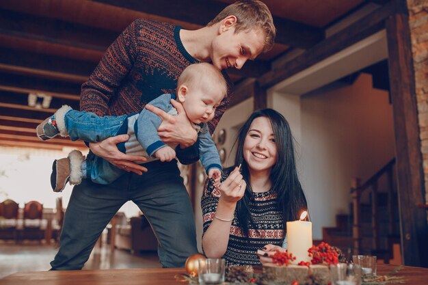 Free photo man with a baby in his hands looking at his wife lighting a candle