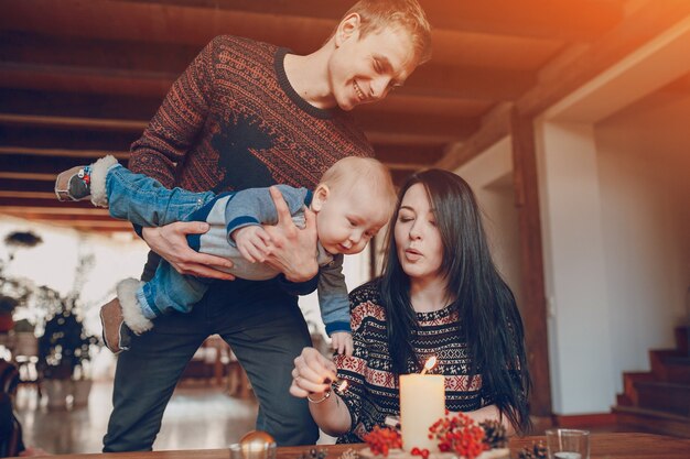 Man with a baby in his hands looking at his wife lighting a candle