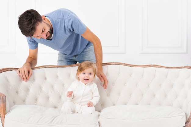 Man with baby on sofa smiling