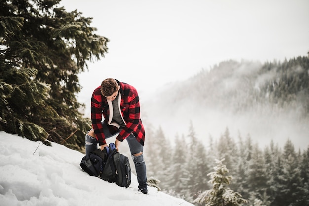 雪の多い丘の上にバックパック付きの男