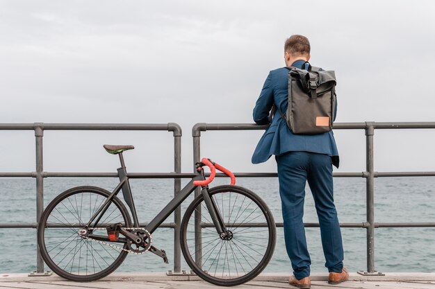 Foto gratuita uomo con zaino in piedi accanto alla sua bici