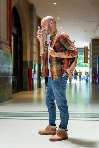 Человек с рюкзаком с помощью мобильного телефона