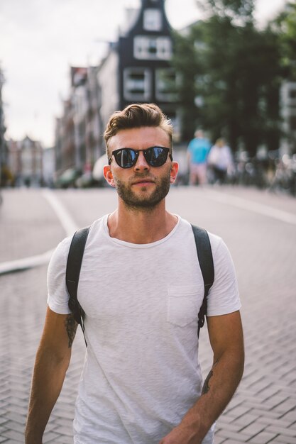 A man with a backpack walks through the streets of Amsterdam.