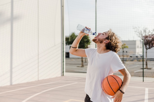 man with basketball drinking water