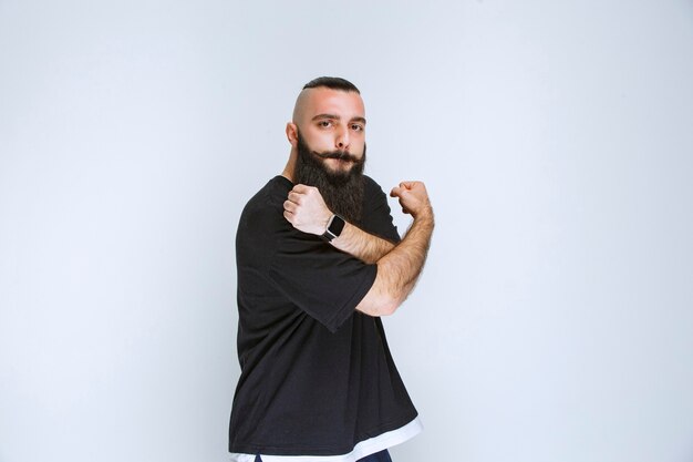 Free photo man with beard demonstrating his arm muscles and feeling powerful.