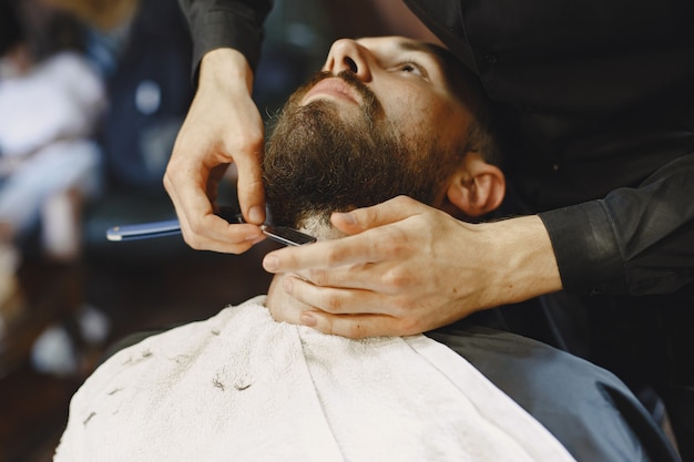 あごひげを生やした男。クライアントと美容師。髭剃りの男。
