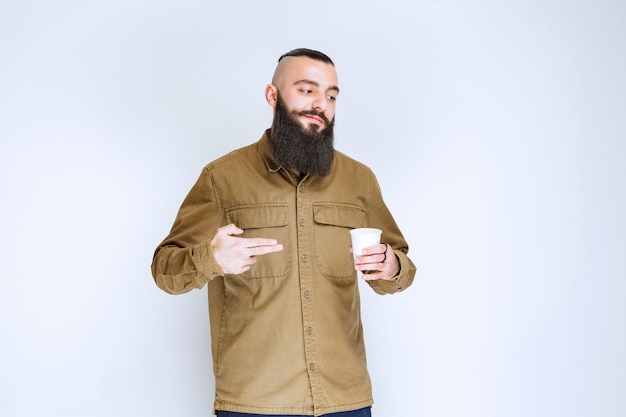 Man with beard holding a cup of coffee in a disposable cup.  