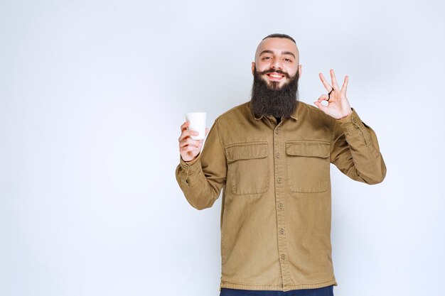 Man with beard holding a cup of coffee and enjoying the taste.