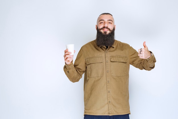 Man with beard holding a cup of coffee and enjoying the taste.