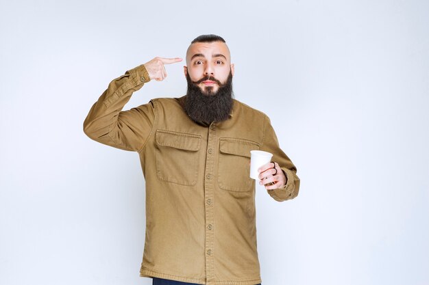 Man with beard holding a cup of coffee and thinking.