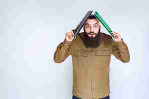 Free photo man with beard holding his folder over his head to protect from rain.