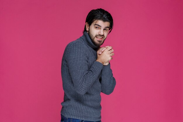 Man with beard holding his hands in a manner like he is praying or wishing something.