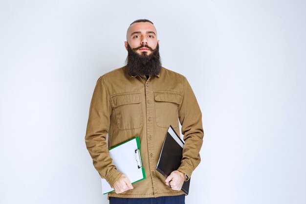 Man with beard holding his report list and waiting with confidence.