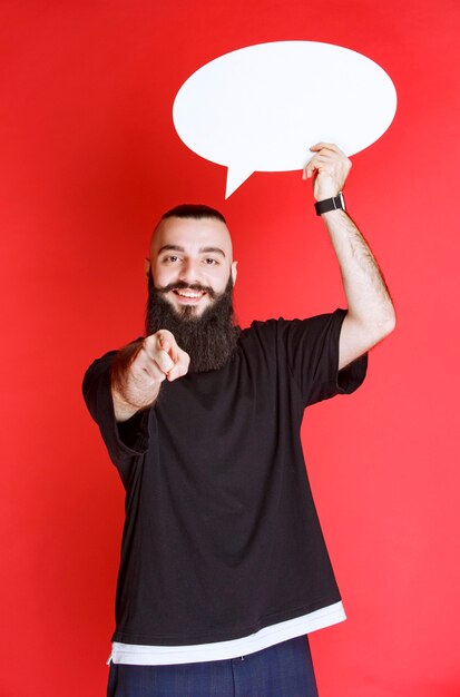 Man with beard holding an ovale thinkboard and pointing
