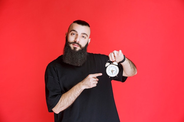 Man with beard holding and promoting an alarm clock as a product.