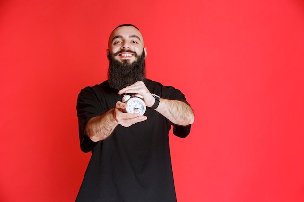 Man with beard holding and promoting an alarm clock as a product.