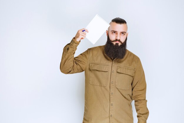 Man with beard holding a quiz paper and looks confused and thoughtful.