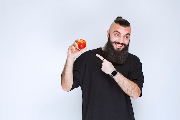 Man with beard holding a red apple or peach. 