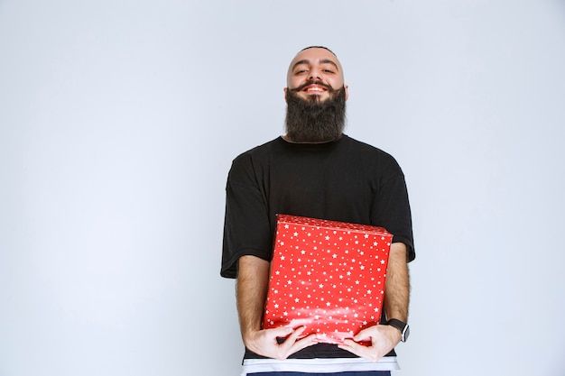 Free photo man with beard holding a red gift box