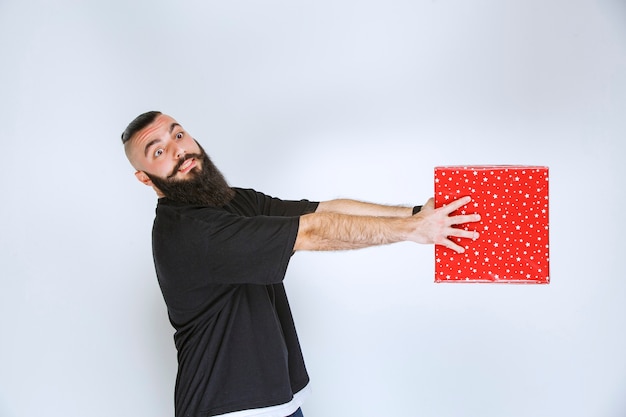 Foto gratuita uomo con la barba che tiene una confezione regalo rossa