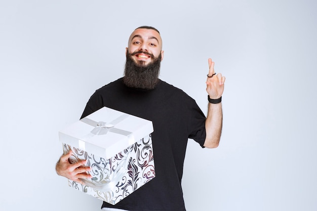 Man with beard holding a white blue gift box smiling and feeling happy. 