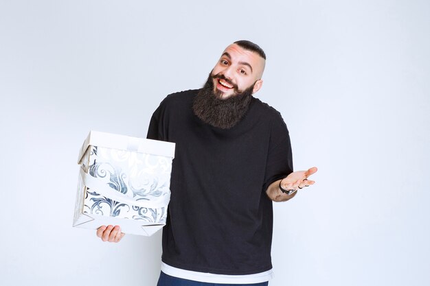 Man with beard holding a white blue gift box smiling and feeling happy. 