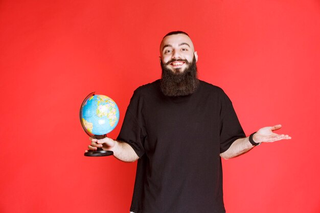 Man with beard holding a world globe.