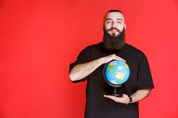 Man with beard holding a world globe.