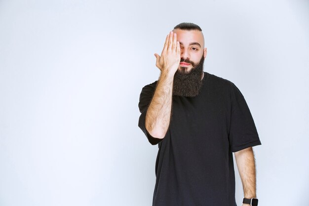 Man with beard looking across his fingers.  