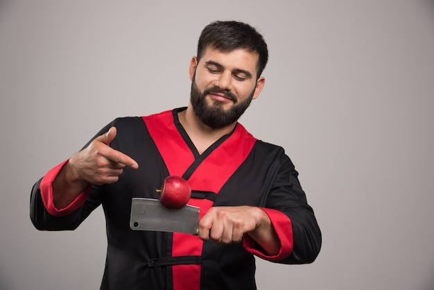ナイフで赤いリンゴを指しているひげを持つ男。
