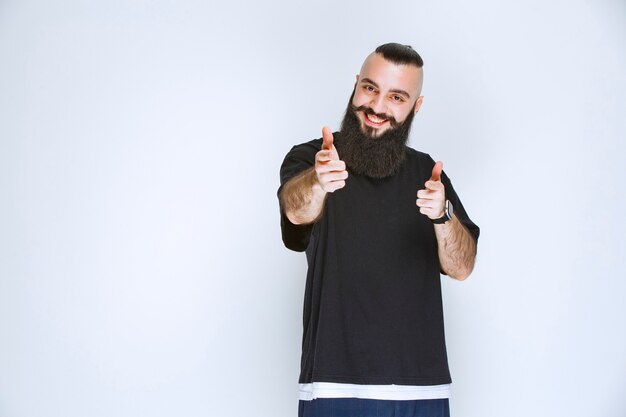 Man with beard pointing at somebody around. 