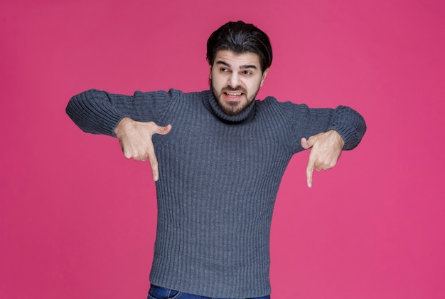 Man with beard pointing on something below.