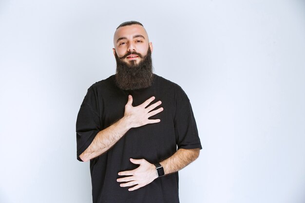 Man with beard putting hand to his heart.