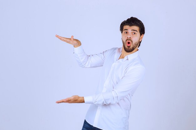 Man with beard showing estimated measures of an object. 