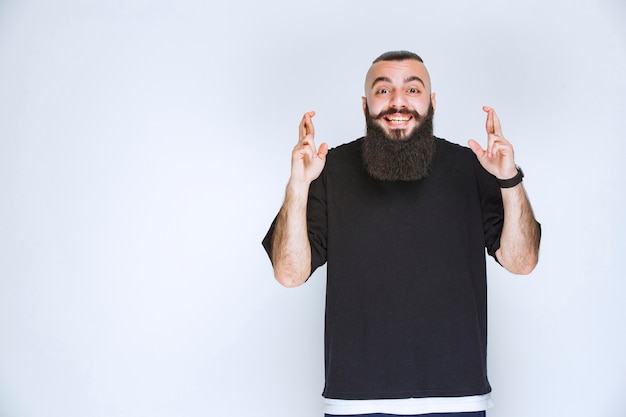 Man with beard showing finger cross sign.  