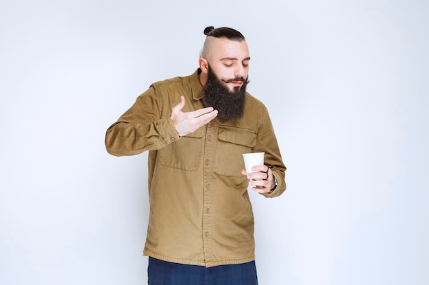 Foto gratuita uomo con la barba che odora il suo caffè.