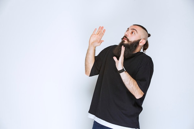 Uomo con la barba che ferma qualcosa con la mano aperta.