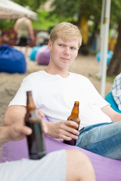 Uomo con birra rilassante tra amici