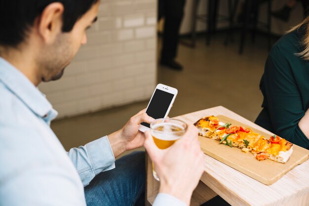 Man with beverage using smartphone in cafe