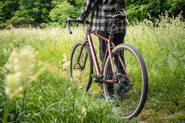 Foto gratuita un uomo con una bicicletta nella foresta tra l'erba