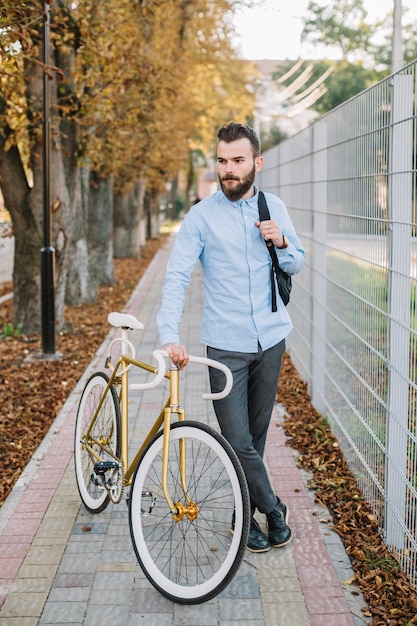 Foto gratuita uomo con la bicicletta vicino al recinto