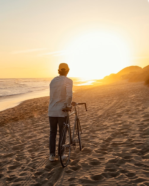 Foto gratuita uomo con la bicicletta in riva al mare full shot