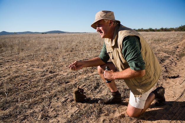 Man with binocular kneeling on landscape